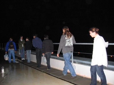 The crew walking along the rooftop ledge at night